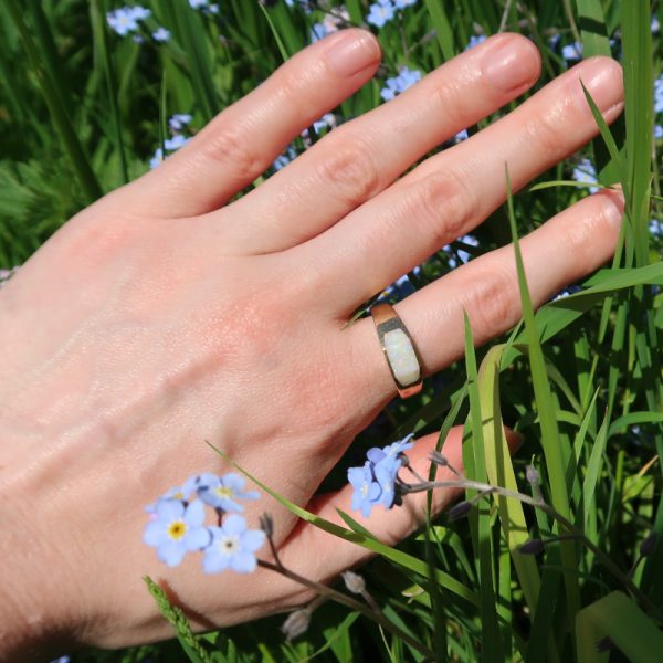 9ct Gold and Opal Ring on finger with grass and forget me nots behind the hand