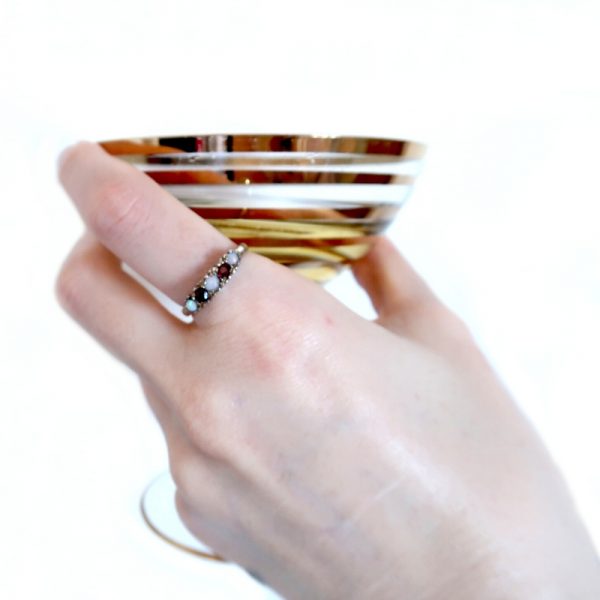 Gold Opal and Ruby Ring on index finger of hand holding vintage champagne glass J003