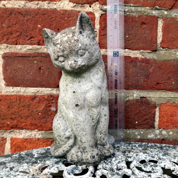 Vintage Cat Garden Ornament sat on white table in front of brick wall with ruler