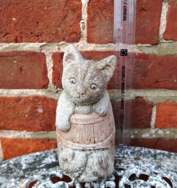 Vintage Cat in a Barrel Garden Ornament in front of brick wall next to a ruler
