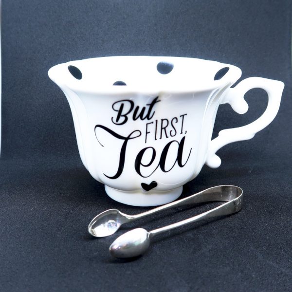 Vintage Sugar Silver Tongs next to black and white spotted teacup